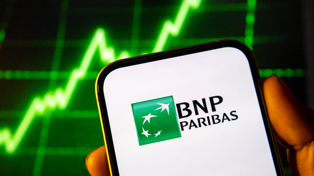 Bnp paribas corporate logo displayed on smartphone screen against a glowing green stock market chart background.