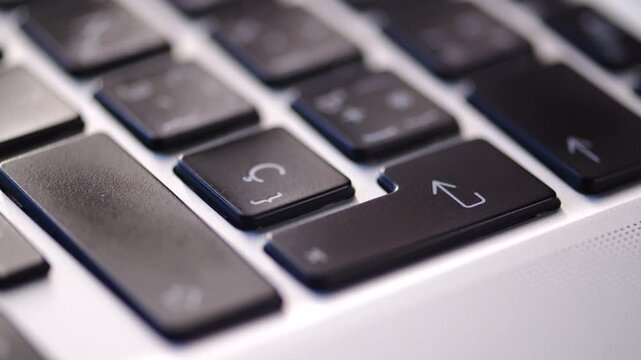 Pressing Enter key on a laptop keyboard close up. Man pushing the enter button on a black keyboard. Commercial concept representing final confirmation.