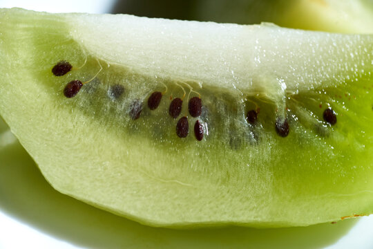 Macro close-up shot of a fresh green kiwi fruit slice showing edible black seeds