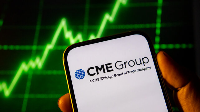 Smartphone screen featuring cme group logo and chicago board of trade company text over green market graph.