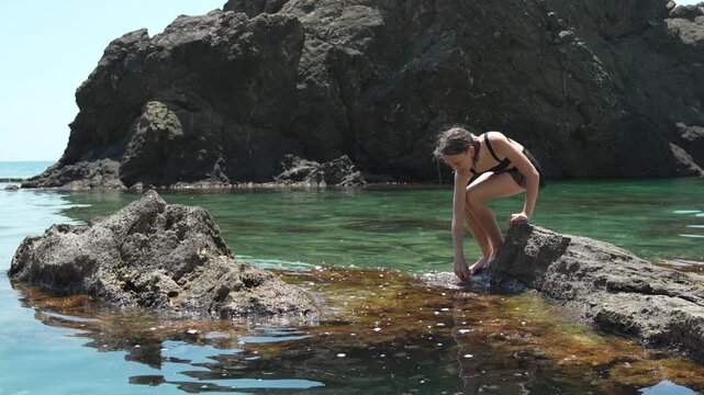 Girl beach rock, young woman standing on stone in clear water, sunny summer day spent at seaside, leisure activity, tranquil nature vacation mood