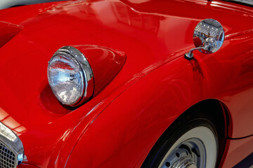 A close-up of the front end of a shiny red vintage car. © SKfoto GE
