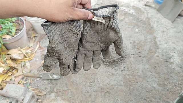 Close Up of Hands Wearing Work Gloves Stained with Fresh Cement