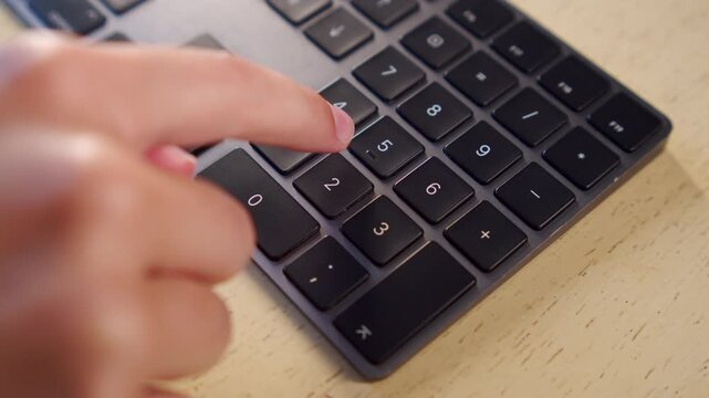 Using a numeric keyboard for calculation. Person calculating numbers on a keyboard. Fingers pressing numbers and math symbols on a computer.