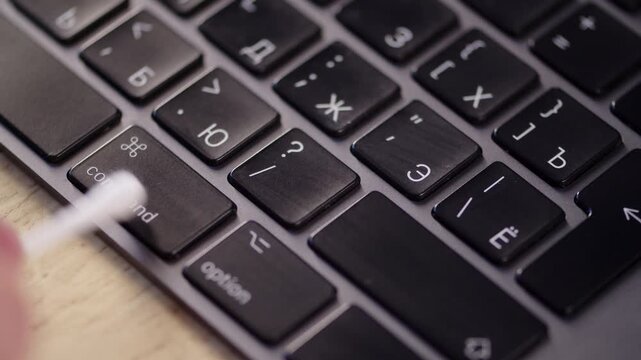  Keyboard detailing. Cleaning a laptop keyboard with a cotton swab. Cleaning a computer. Hygiene for devices. Washing the laptop.