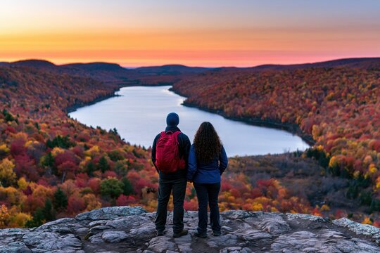 Hiking couple enjoying a scenic lake view at sunset during a vibrant autumn travel