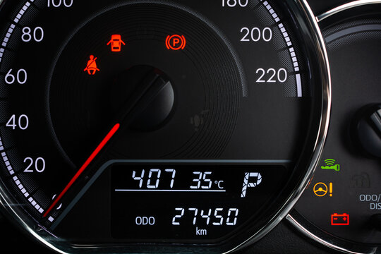 Close-up of modern car dashboard displaying digital odometer, speedometer, and illuminated warning lights