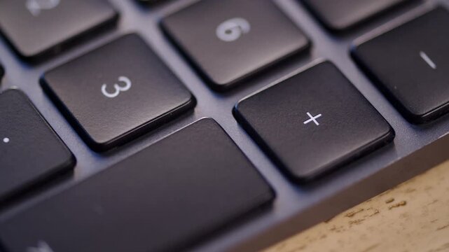 Pressing plus key close up. Pushing the addition button on a numeric keyboard. Computer with a 100% keyboard.