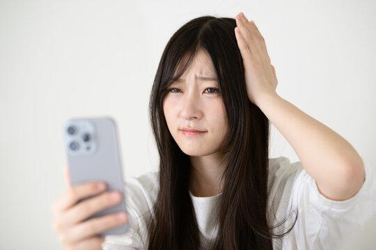 スマートフォンを見て悩む日本人女性