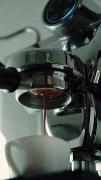 4K Pouring coffee stream from professional machine in cup. Barista man making double espresso, using filter holder. Flowing fresh ground coffee. Drinking roasted black coffee in the morning.
