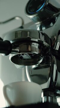 4K Pouring coffee stream from professional machine in cup. Barista man making double espresso, using filter holder. Flowing fresh ground coffee. Drinking roasted black coffee in the morning.