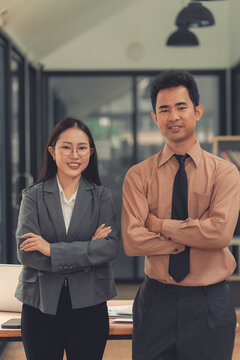 Two Asian business colleagues discussing work project on digital tablet in office.