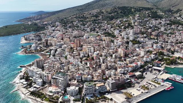 Saranda, Albania. Aerial 4K panoramic drone view of the Ionian Sea, port, boats and Mediterranean urban architecture. Majestic view of the resort town and its beaches.