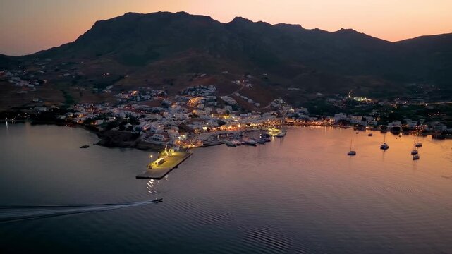 Aerial view of the illuminated town of Livadi, harbor and marina of Serifos island, during summer dusk, Cyclades, Greece