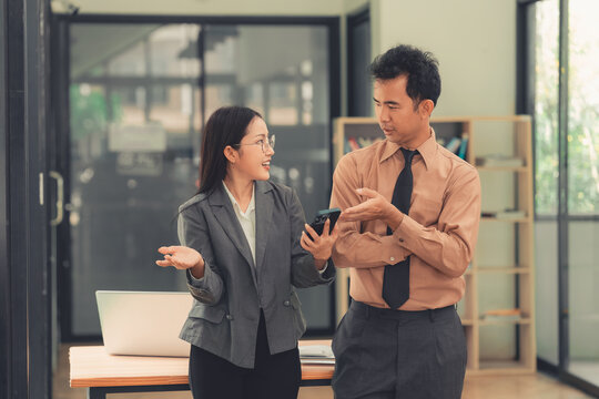 Two Asian business colleagues discussing work project on digital tablet in office.
