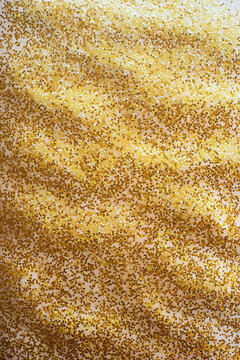 Vertical high resolution background texture of rippled golden sand infused with intense shimmering golden glitter