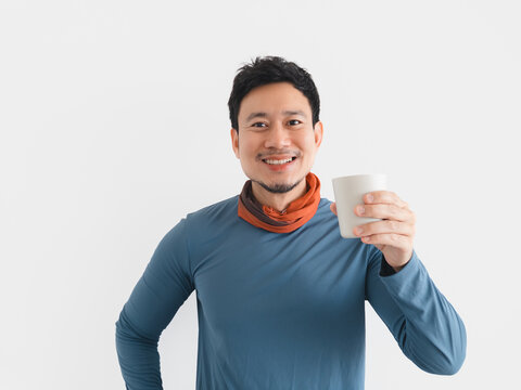 Smiling Asian man holding a white cup, wearing a blue shirt and neck gaiter.