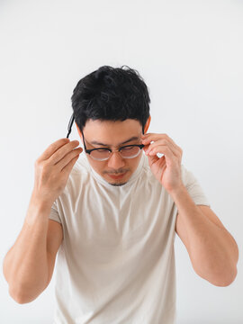 Young Asian man adjusting his eyeglasses, looking down with a focused and thoughtful expression.
