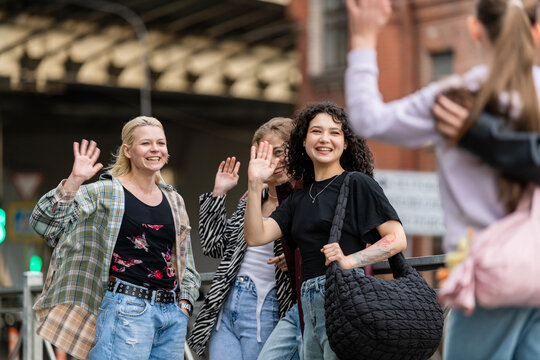Young diverse friends smiling and waving on a city street