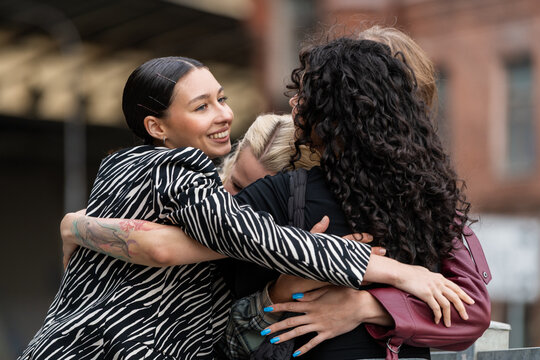 Happy group of diverse friends hugging outdoors