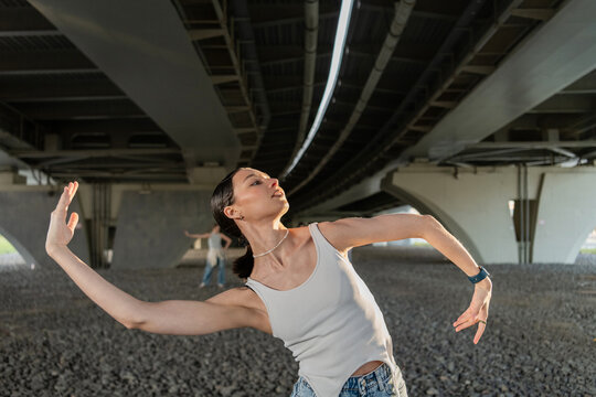 Young woman dancing gracefully under an urban overpass