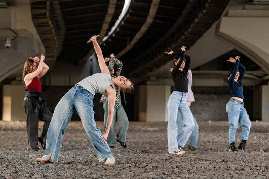 Young women performing a dance routine under a bridge