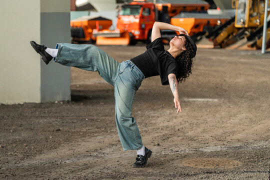 Young woman strikes a floating dance pose outside