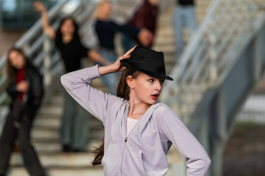 Teenage girl in a fedora striking a dance pose
