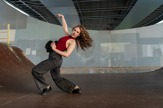 Female dancer striking a dramatic pose under a bridge
