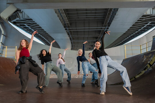 Young female dance crew striking a pose under a bridge