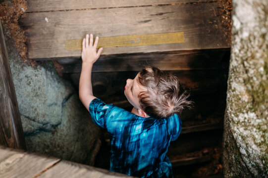 Curious young boy climbs up rustic stairs