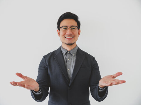 Smiling Asian businessman presenting with open hands, offering a warm welcome or introduction.