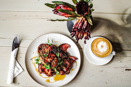 Flat lay of gourmet brunch with coffee and protea flowers