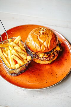Gourmet cheeseburger with fries on an orange plate