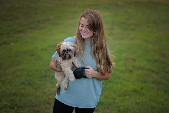 Smiling young woman holding her shih tzu puppy
