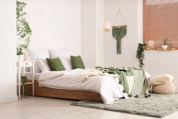 Fototapeta premium Interior of bedroom with table, pouf and green plants
