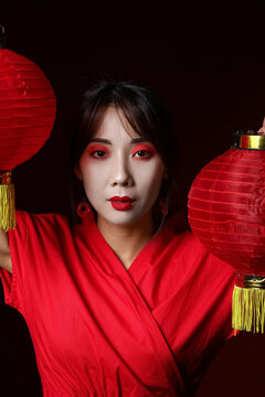 Beautiful young geisha in traditional clothes with lanterns on black background