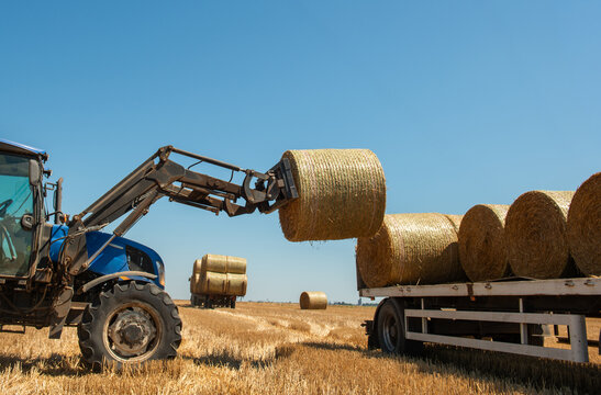  Tractor loading hay bales on truck trailer