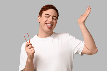 Fototapeta premium Young man with tongue scraper on grey background