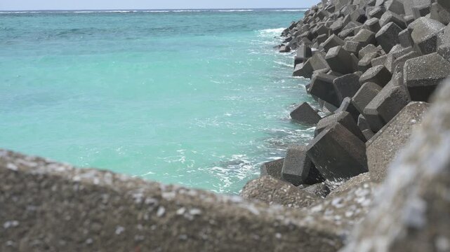 手前の消波ブロック越しに眺めるエメラルドグリーンの美しい海