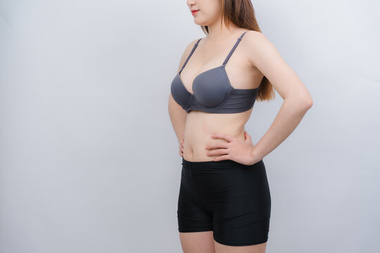 Woman in Underwear: A woman in a grey bra and black shorts stands with her hands on her hips, displaying a confident posture.