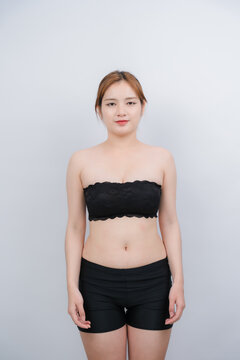Young Woman in Activewear: A confident young woman posing in a comfortable black top and shorts, radiating natural beauty and physical wellness in a minimalist setting.