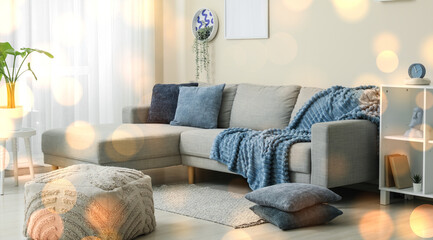 Modern living room interior with comfortable gray sectional sofa blue throw blanket decorative pillows and soft lighting © Pixel-Shot