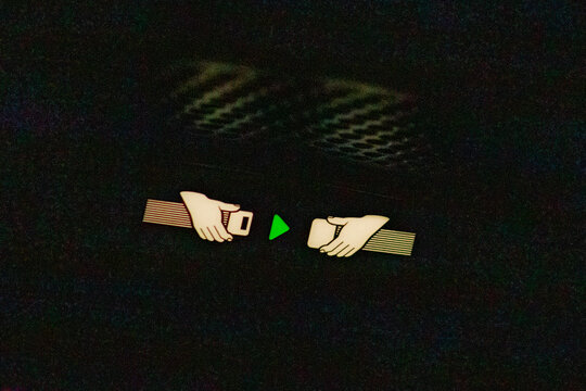 Manchester, UK &ndash; July 28, 2026: Illuminated seat belt fastening sign inside dark aircraft cabin