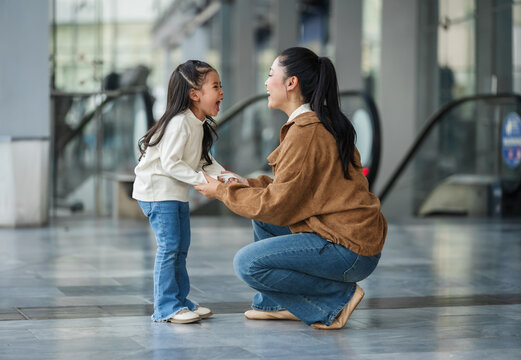 excited child girl laughing with her mother in shopping mall or department store
