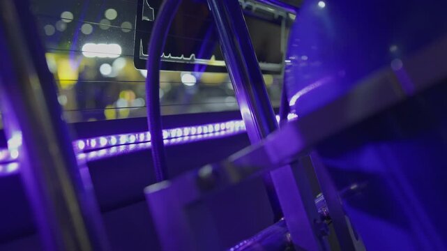 Close-up cinematic shot inside a vehicle or cabin with ambient orange LED strip lighting reflecting off interior metal structures and glass with background bokeh.