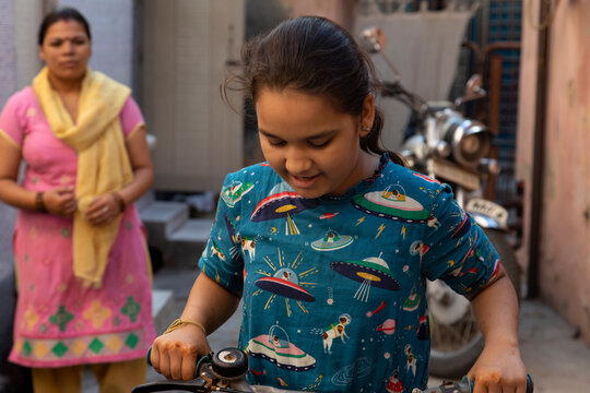 mother looking at her daughter ride a bicycle