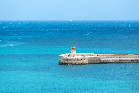 View of the harbor entrance and the old medieval Ricasoli East Breakwater with its lighthouse, standing above turquoise Mediterranean waters at the gateway to Valletta&rsquo;s Grand Harbour