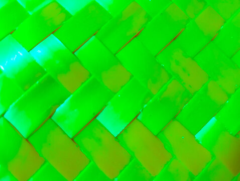 Glowing neon green and orange rectangular blocks form a detailed, interlocking woven pattern structure.