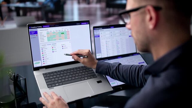 IT Manager Reviews Compliance Dashboard On Dual Touchscreen Laptop